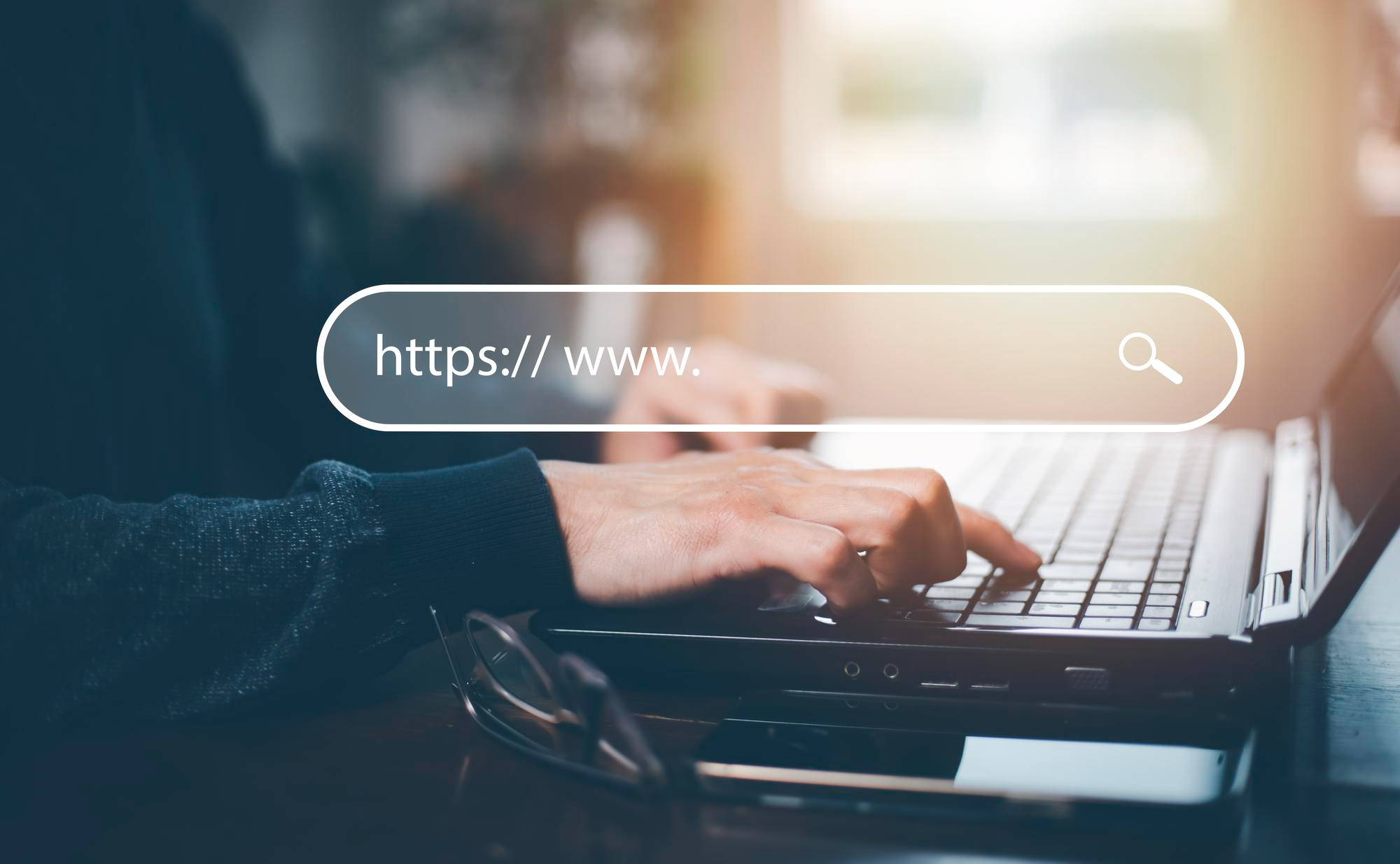 Osoba wpisująca adres strony internetowej na laptopie — strony i sklepy w abonamencie